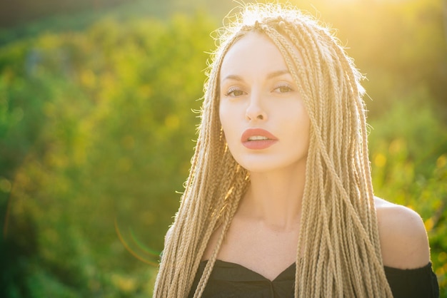 Sonniges Sommerporträt. Haarpflegekonzept. Sinnliches Frauenportrait. Modefrau mit langen Haardreadlocks. Mädchen im Freien.