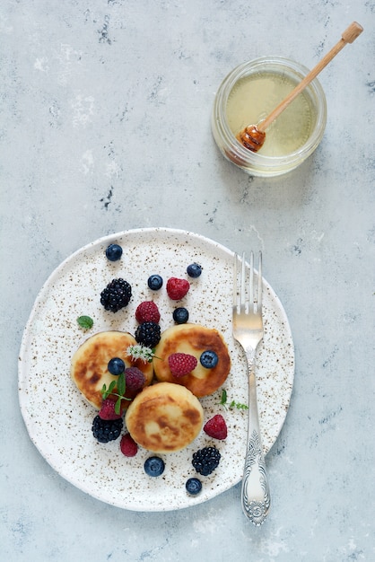 Sonntagsfrühstück mit Käsekuchen, Honig, frischen Beeren und Minze