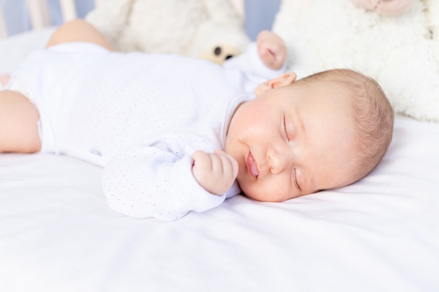 Sono saudável de um bebê recém-nascido em um berço no quarto com um urso de pelúcia em uma cama de algodão