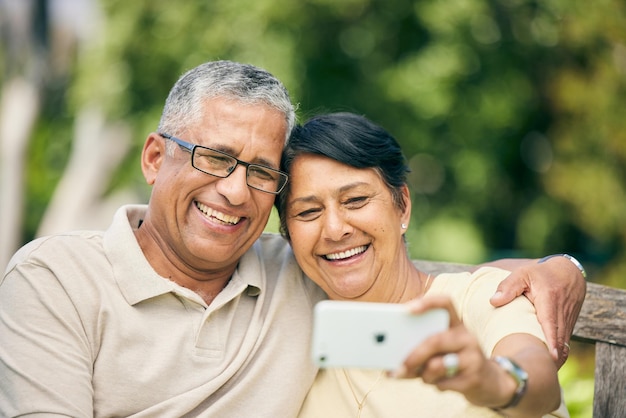 Sonreír a una pareja mayor y tomarse una selfie en la naturaleza del parque o en el campo al aire libre uniéndose y amándose Foto de perfil feliz y un anciano y una mujer tomando fotos para recordar las redes sociales o la jubilación