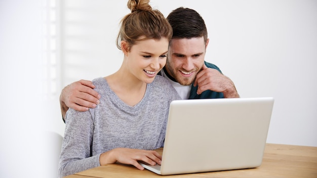 Sonríe en casa o en pareja en la computadora portátil para elegir leer un artículo en línea en el sitio web de diseño de interiores abrazar la opción de alquiler de casas o personas felices escribiendo en tecnología para la renovación de la investigación hipoteca o préstamo