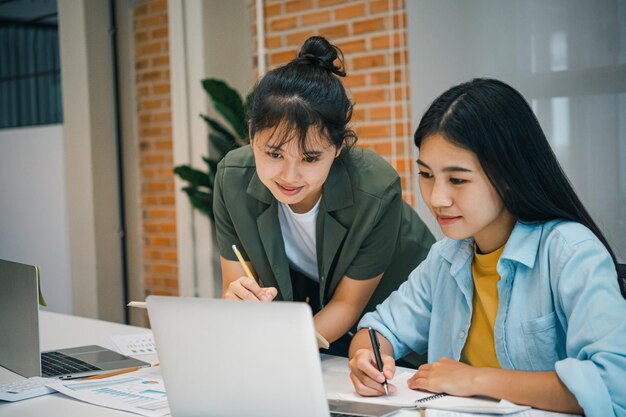 Sonríe mujer de negocios asiática sentada trabajando en una computadora portátil en el negocio de gestión financiera de la oficina