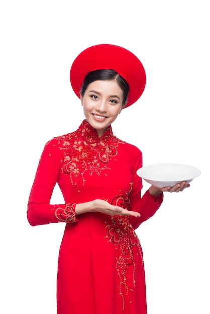 Sonríe a la mujer vietnamita en el vestido tradicional Ao Dai e introduce el producto sobre fondo blanco.