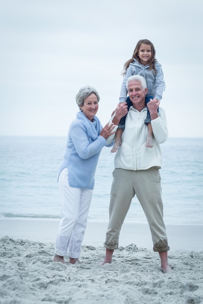 Sonriendo abuelos con nieta en la playa