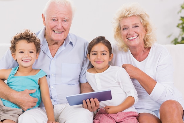 Sonriendo abuelos con niños usando una tablet pc