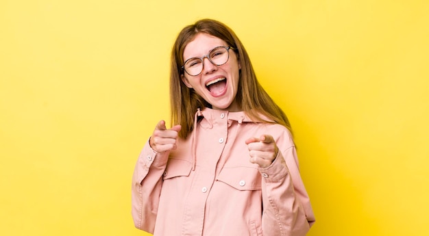 Sonriendo con una actitud feliz exitosa positiva apuntando a la cámara haciendo un signo de arma con las manos