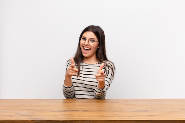 sonriendo con una actitud positiva, exitosa y feliz apuntando al frente, haciendo un signo de arma con las manos