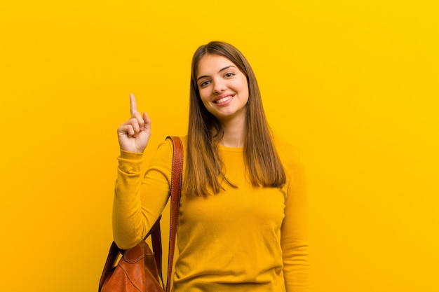 sonriendo alegre y alegremente, apuntando hacia arriba con una mano para copiar espacio