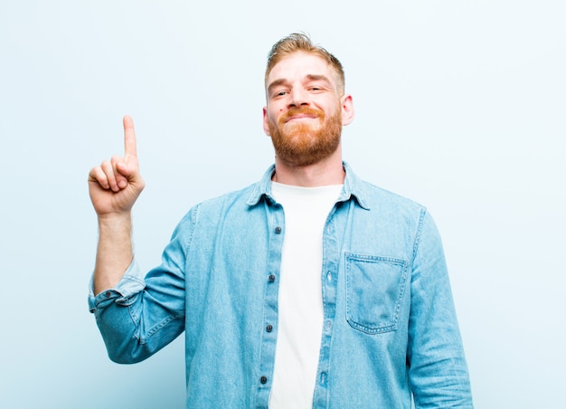 sonriendo alegre y alegremente, apuntando hacia arriba con una mano para copiar espacio