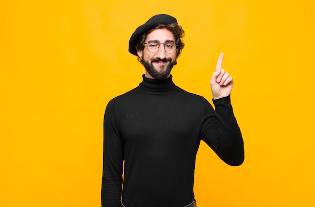 sonriendo alegre y alegremente, apuntando hacia arriba con una mano para copiar espacio