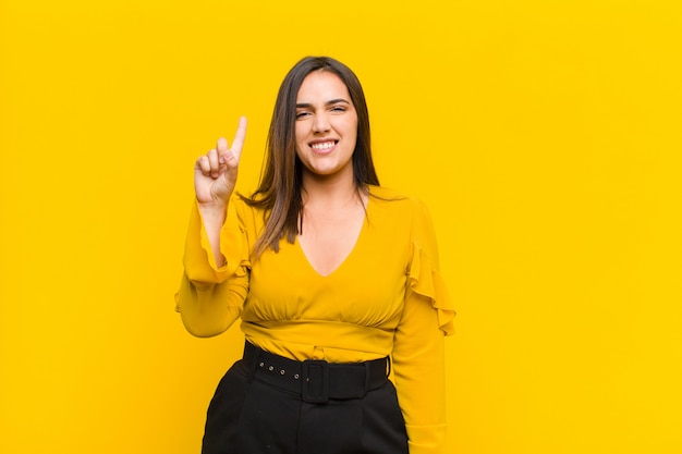 sonriendo alegre y alegremente, apuntando hacia arriba con una mano para copiar espacio