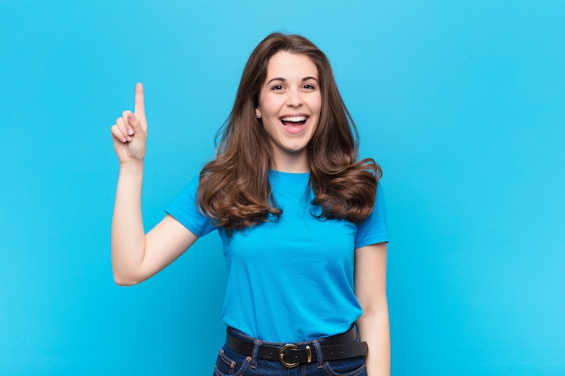 sonriendo alegre y alegremente, apuntando hacia arriba con una mano para copiar espacio