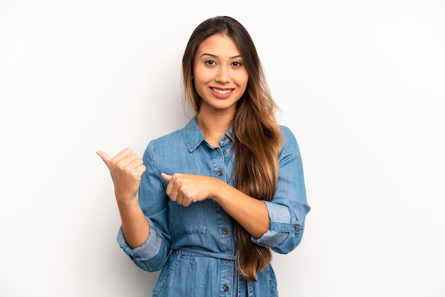 Sonriendo alegre y casualmente señalando el espacio de copia en el costado sintiéndose feliz y satisfecho