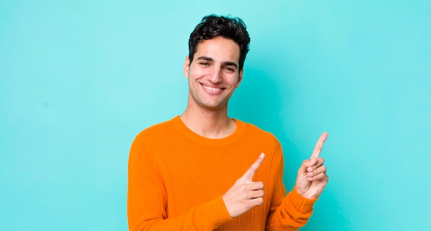 Sonriendo alegremente y apuntando hacia un lado y hacia arriba con ambas manos mostrando el objeto en el espacio de la copia