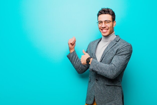 sonriendo alegremente y casualmente apuntando a copiar espacio en el costado, sintiéndose feliz y satisfecho