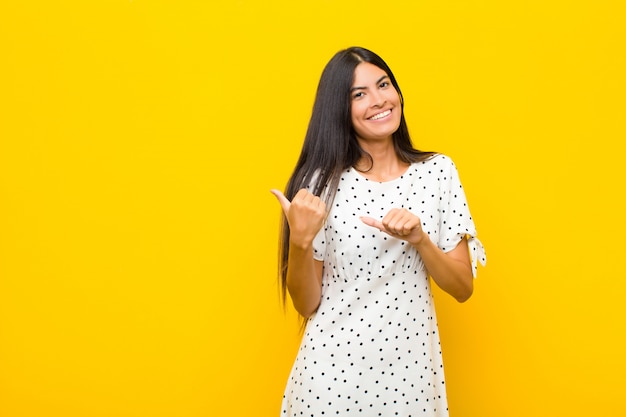 sonriendo alegremente y casualmente apuntando a copiar espacio en el costado, sintiéndose feliz y satisfecho