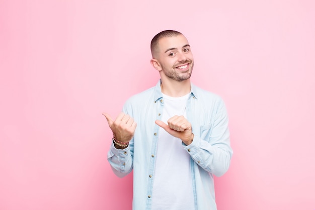 sonriendo alegremente y casualmente apuntando a copiar espacio en el costado, sintiéndose feliz y satisfecho