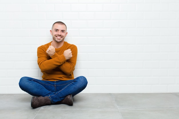 sonriendo alegremente y celebrando, con los puños cerrados y los brazos cruzados, sintiéndose feliz y positivo