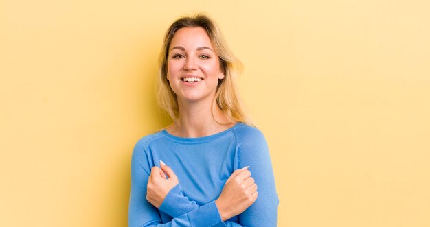 sonriendo alegremente y celebrando con los puños cerrados y los brazos cruzados sintiéndose feliz y positivo