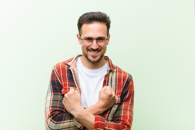 sonriendo alegremente y celebrando, con los puños cerrados y los brazos cruzados, sintiéndose feliz y positivo