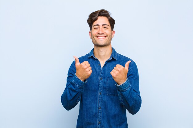 sonriendo alegremente y luciendo feliz, sintiéndose despreocupado y positivo con ambos pulgares arriba