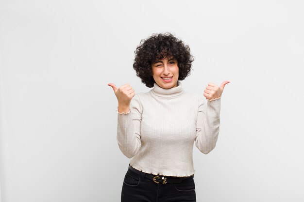 sonriendo alegremente y luciendo feliz, sintiéndose despreocupado y positivo con ambos pulgares arriba