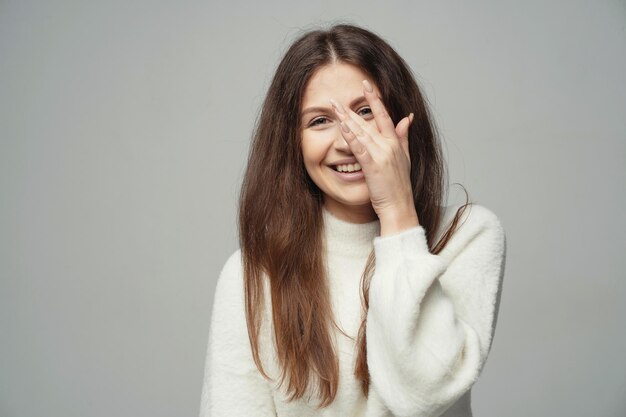 Sonriendo alegremente muestra un gesto con los dedos cerca de la cara de una mujer morena