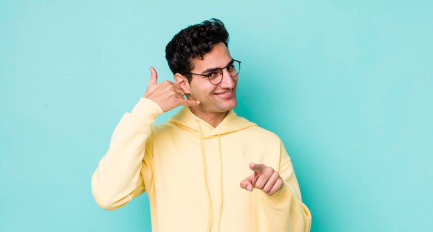 Sonriendo alegremente y señalando a la cámara mientras hace una llamada, luego gesticula hablando por teléfono