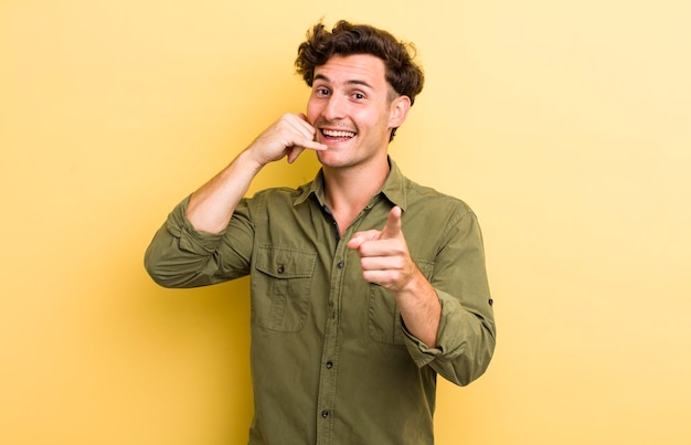 Sonriendo alegremente y señalando a la cámara mientras hace una llamada, luego gesticula hablando por teléfono