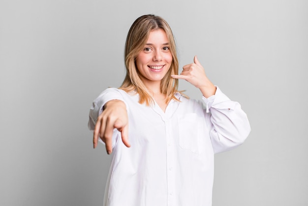 Foto sonriendo alegremente y señalando a la cámara mientras hace una llamada, luego gesticula hablando por teléfono