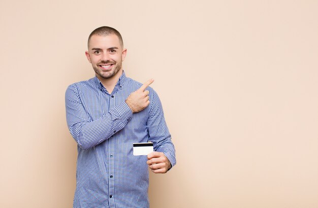 sonriendo alegremente, sintiéndose feliz y apuntando hacia un lado y hacia arriba, mostrando el objeto