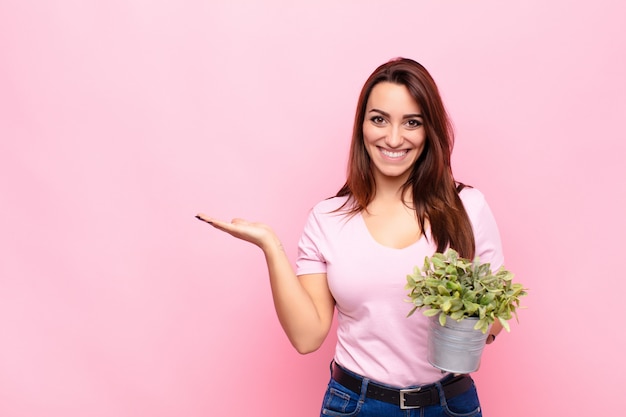 sonriendo alegremente, sintiéndose feliz y mostrando un concepto en el espacio de la copia con la palma de la mano