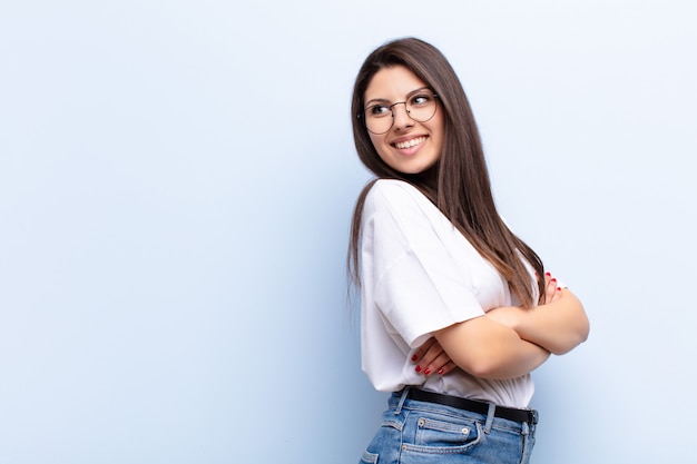 sonriendo alegremente, sintiéndose feliz, satisfecho y relajado, con los brazos cruzados y mirando a un lado