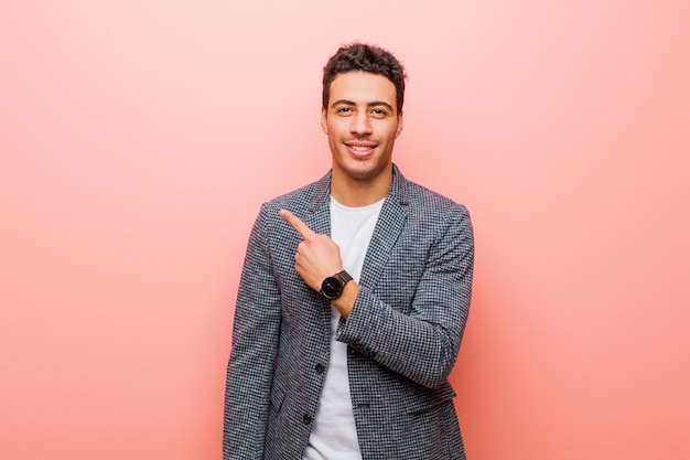 sonriendo alegremente, sintiéndose feliz y señalando hacia un lado y hacia arriba, mostrando el objeto en el espacio de la copia
