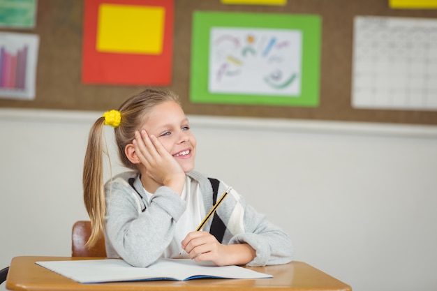 Sonriendo alumno soñando despierto en un aula