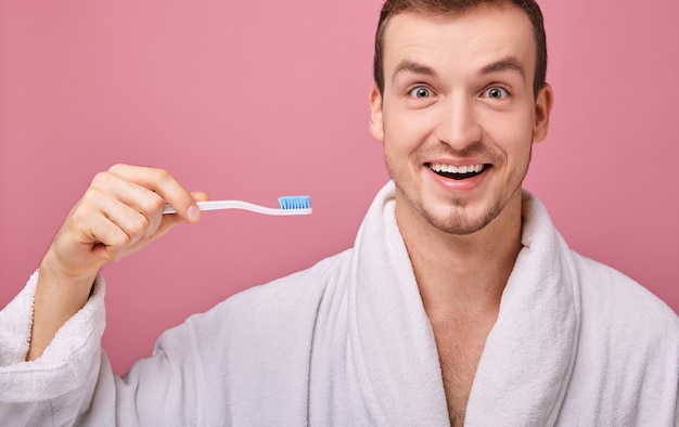 Sonriendo ampliamente hombre de túnica blanca con el cepillo de dientes feliz