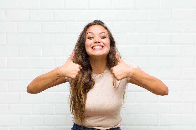 sonriendo ampliamente luciendo feliz, positivo, seguro y exitoso, con ambos pulgares hacia arriba