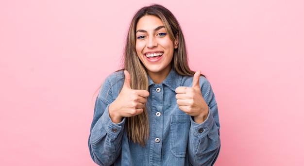 sonriendo ampliamente mirando feliz positivo seguro y exitoso con ambos pulgares arriba