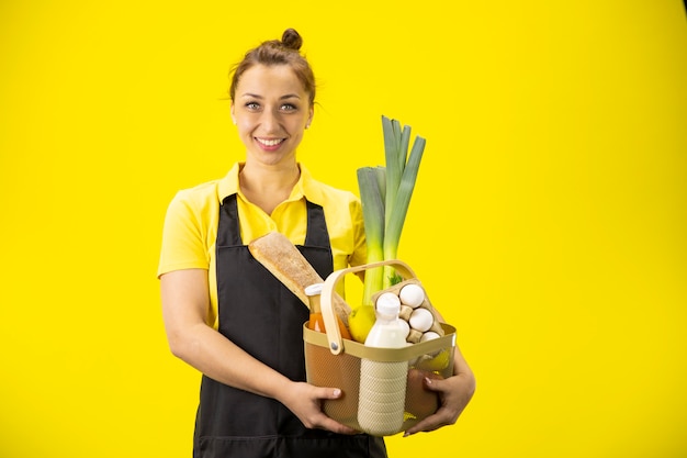 Sonriendo atractivo agricultor en uniforme con cesta con comestibles productos agrícolas