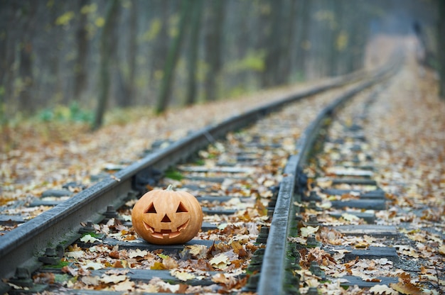 Sonriendo calabaza de halloween en los rieles en el bosque