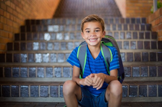 Sonriendo colegial sentado en la escalera