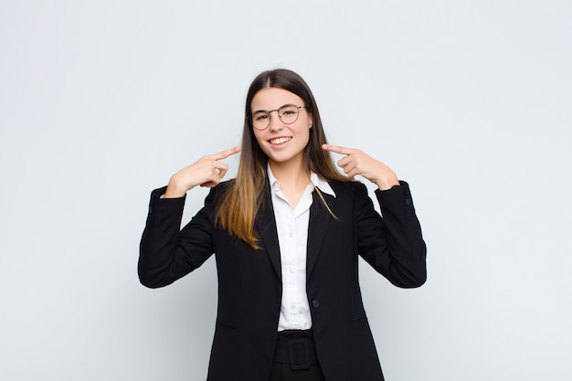 sonriendo con confianza apuntando a su propia sonrisa amplia, actitud positiva, relajada y satisfecha