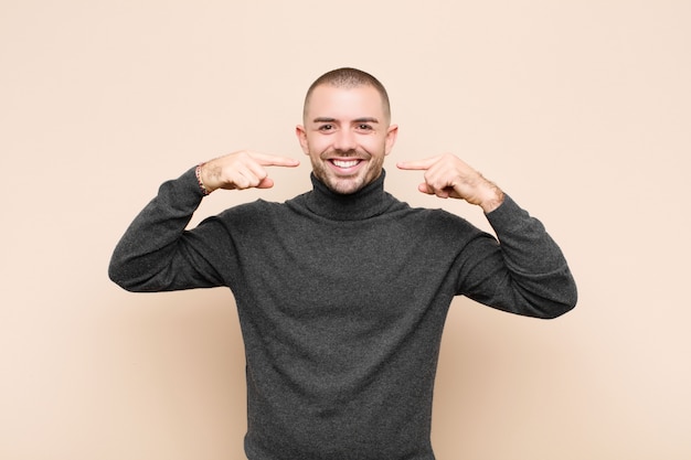 sonriendo con confianza señalando su propia sonrisa amplia, actitud positiva, relajada y satisfecha