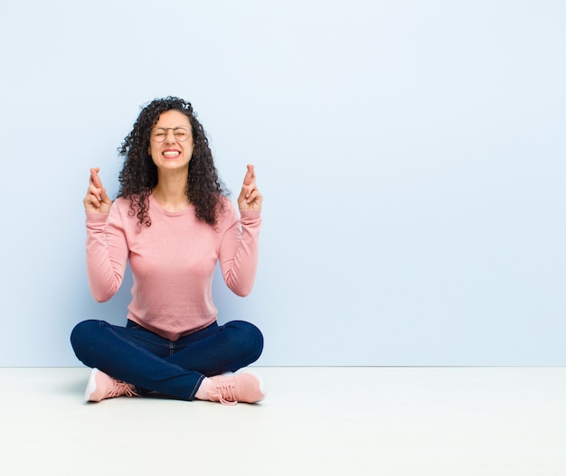 sonriendo y cruzando ambos dedos con ansiedad, sintiéndose preocupado y deseando o esperando buena suerte