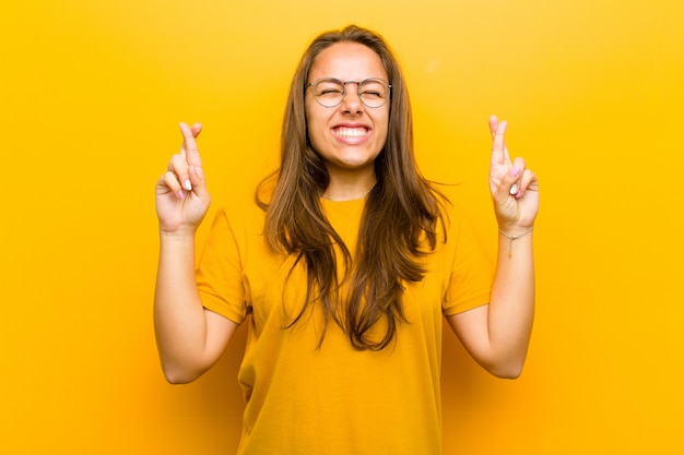 sonriendo y cruzando ansiosamente ambos dedos, sintiéndose preocupado y deseando o esperando buena suerte