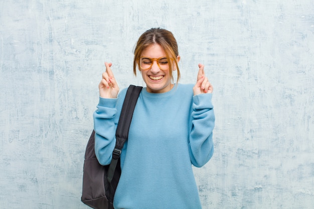 sonriendo y cruzando ansiosamente ambos dedos, sintiéndose preocupado y deseando o esperando buena suerte