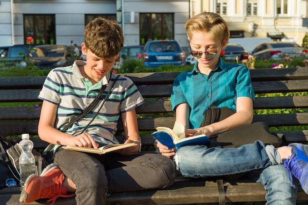 Sonriendo dos colegiales leyendo libros