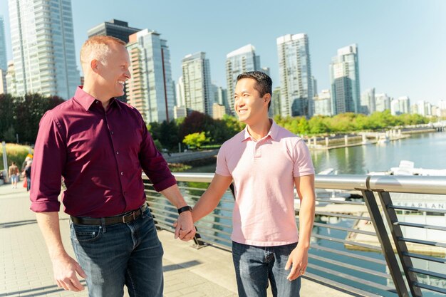 Sonriendo dos hombres homosexuales pareja gay cogidos de la mano mirándose caminando por la calle Fecha