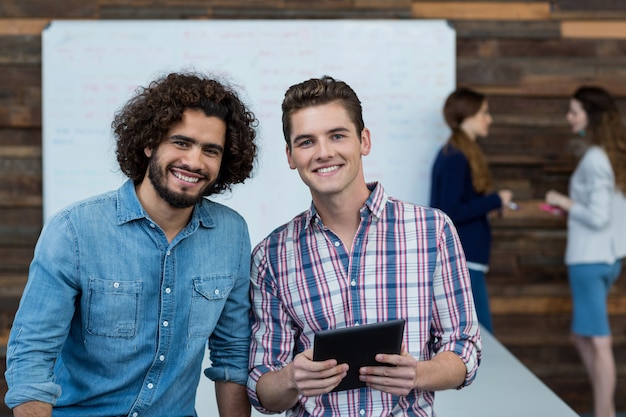 Sonriendo ejecutivos de negocios de pie en la oficina con tableta digital