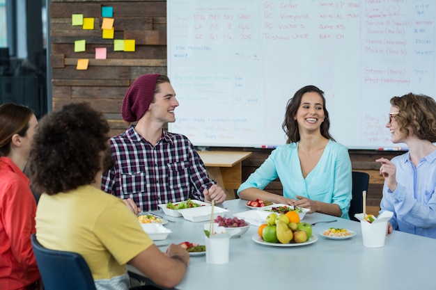 Sonriendo ejecutivos de negocios que tienen comida en la oficina